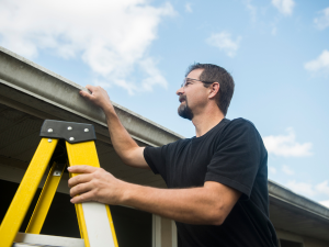 Homeowner inspecting shingles for damage on the roof. Call your local Moraga roofer for professional assistance.